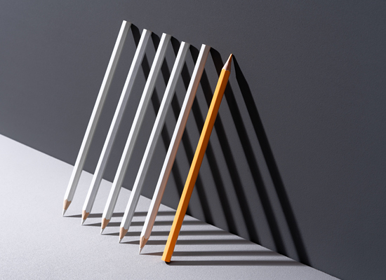  6 pencils stood up, leaning against a wall