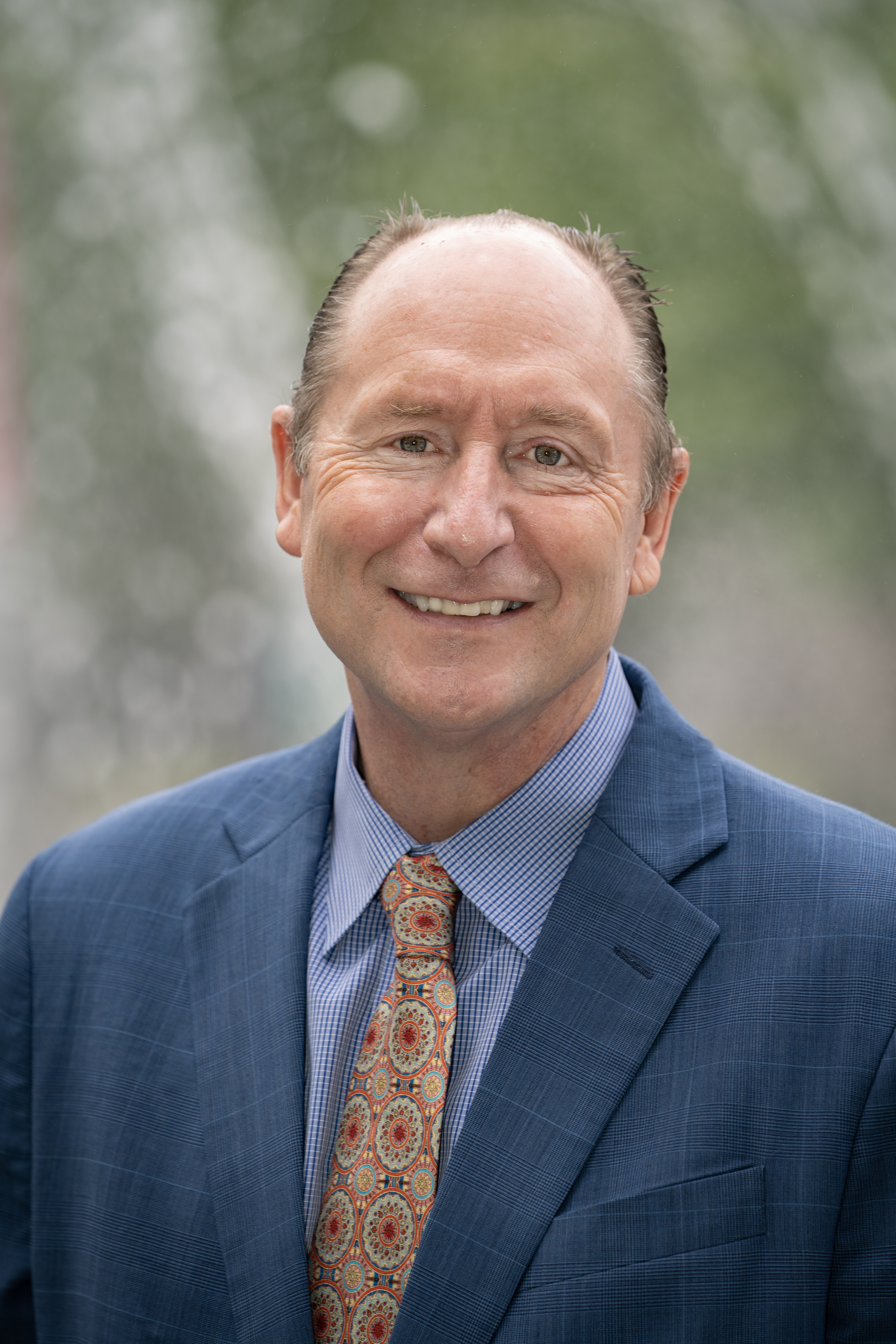 David Wrobel, wearing a blue suit, striped light blue shirt and patterned orange tie